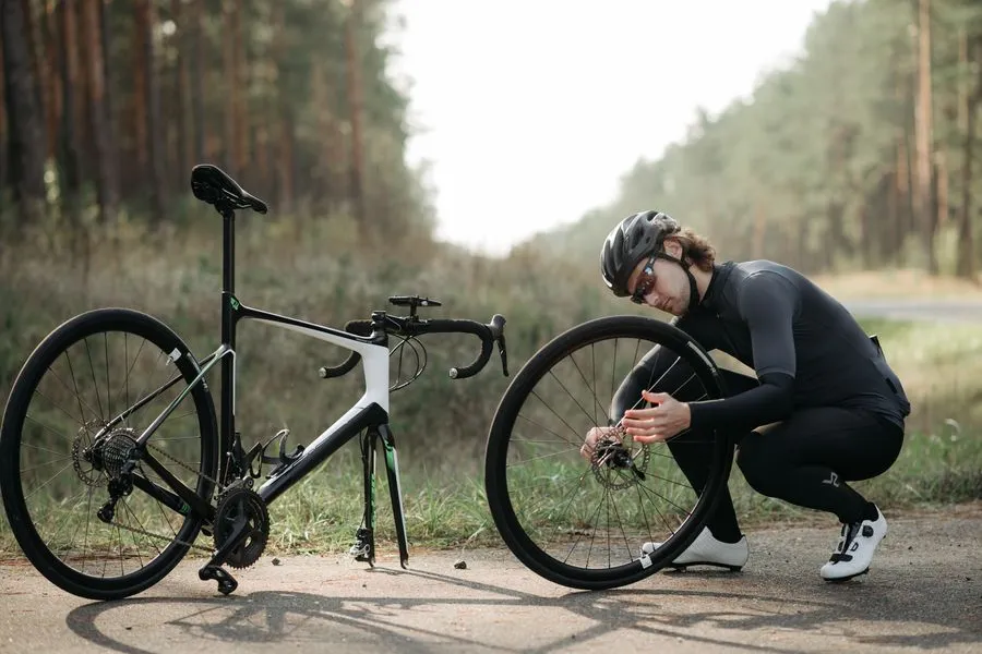 Cyclist repairing a bicycle wheel at the roadside away from a workshop